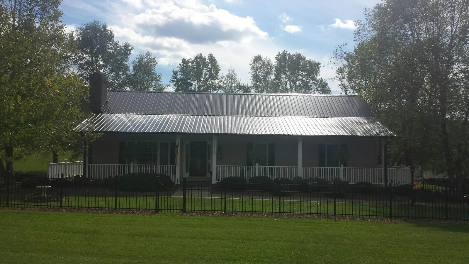 Gray metal roof on a brick ranch with a full width front porch — Gutter Guard Installation work by our crew in Windsor